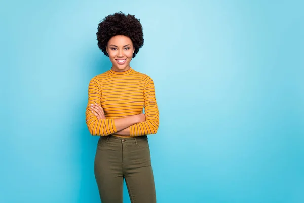 Foto di incredibile bella pelle scura ondulata signora dentata raggio sorridente buon umore braccia incrociate indossare casual pantaloni a righe maglione isolato colore blu sfondo — Foto Stock