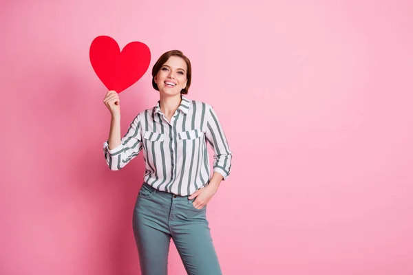 Retrato de menina adorável alegre desfrutar 14-fevereiro celebração realizar grande cartão de papel vermelho surpresa do coração de seu namorado usar roupa moderna isolado sobre cor rosa fundo — Fotografia de Stock