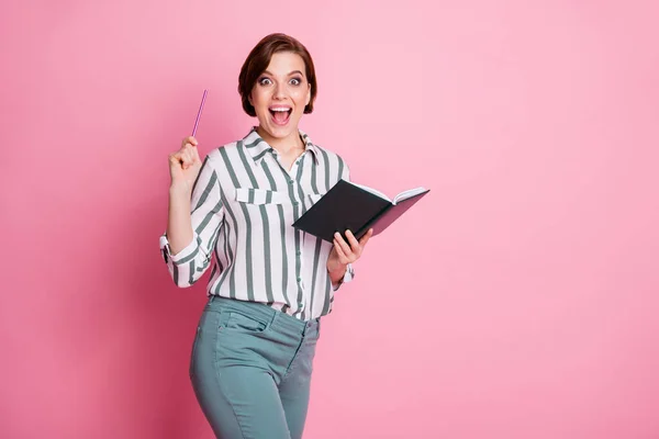 Omg ideia incrível. Menina estudante impressionado escrever ensaio segurar livro cópia levantar lápis gritar wow inacreditável desgaste cinza calças brancas calças isoladas sobre cor rosa fundo — Fotografia de Stock