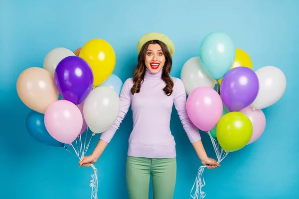 Foto van vrij grappige dame dragen veel kleurrijke luchtballonnen onverwachte verrassing partij dragen paarse trui baret cap groene broek geïsoleerde blauwe kleur achtergrond — Stockfoto