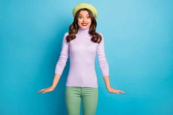 Fénykép a csodálatos utazó hölgy sugárzó mosolygós stílusos megjelenés jó hangulat viselet modern zöld sapka kalap lila garbó jumper nadrág elszigetelt kék háttér — Stock Fotó