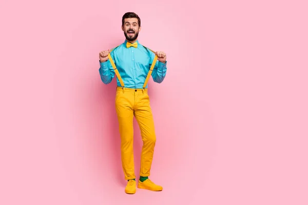 Volledige lengte body size weergave van zijn hij mooi aantrekkelijk vrolijk vrolijk funky kerel dragen munt shirt geel broek kleding trekken bretels hebben plezier geïsoleerd op pastel roze kleur achtergrond — Stockfoto