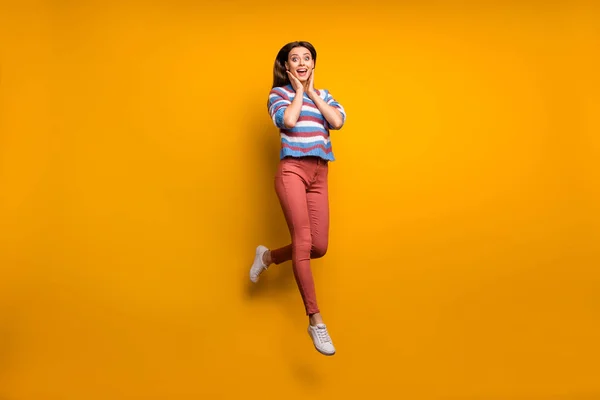 Foto em tamanho completo de menina surpreendida olhar bom incrível desconto impressionado salto sentir regozijar-se gritar toque mãos rosto desgaste camisola calçado isolado sobre fundo de cor brilhante — Fotografia de Stock