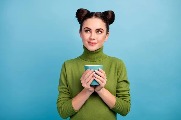 Photo of attractive teen lady hold hot beverage cup tea enjoy weekend morning look empty space dreamer wear warm green turtleneck sweater isolated blue color background — Stock Photo, Image