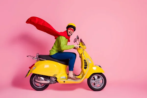 Profil boční pohled na jeho pěkný atraktivní blázen přešťastný veselý veselý chlap řízení moped rychlé nošení plášť záchrana bezpečná planeta izolované přes růžové pastelové barvy pozadí — Stock fotografie
