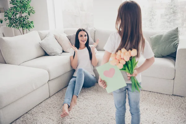 Фото симпатичной маленькой девочки очаровательная брюнетка мама ждет 8 марта настоящее девушка прячет открытки тюльпаны цветы положительные нежные эмоции сидя на полу дома — стоковое фото