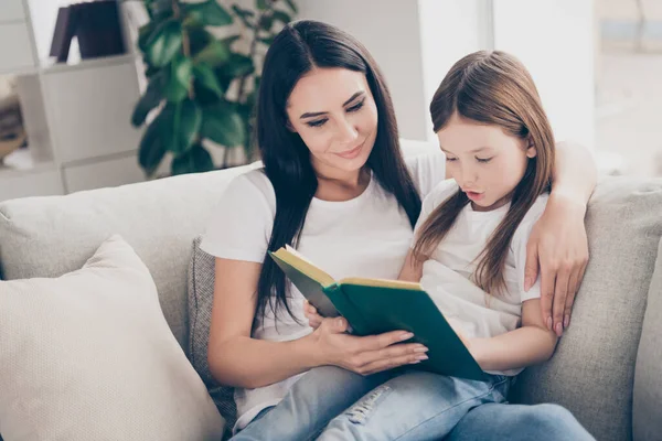 Портрет двох каштанових людей мила дбайлива мати вчить її дочку читати книгу дівчина зосереджена сидіти диван у вітальні будинку — стокове фото