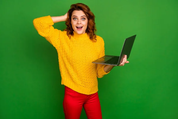 Photo of funny business lady administrator hold notebook hands browsing IT website arm on head read cool good news wear yellow knitted pullover red pants isolated green color background — Zdjęcie stockowe