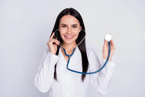 Fénykép a gyönyörű vidám professzionális doc lady jókedv barátságos mosolygós beteg sztetoszkóppal hallgatni szívverés kopás fehér laborköpeny elszigetelt szürke színű háttér — Stock Fotó