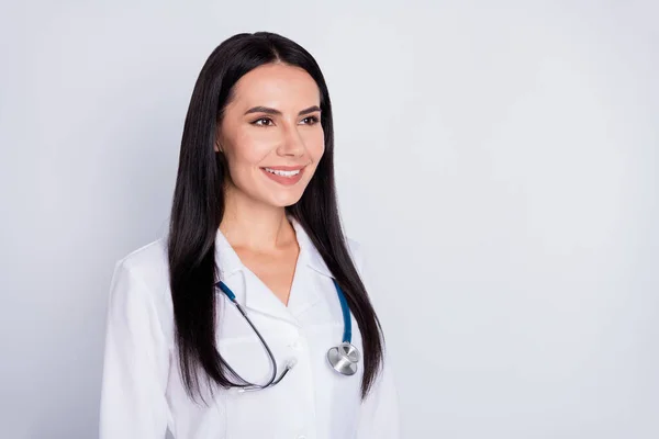 Φωτογραφία από ελκυστικό επαγγελματία ιατρό ειδικευόμενη κυρία καλή διάθεση φιλικό χαμόγελο αναζητούν ασθενή φορούν λευκό στηθοσκόπιο παλτό εργαστήριο απομονωμένο γκρι φόντο χρώμα — Φωτογραφία Αρχείου