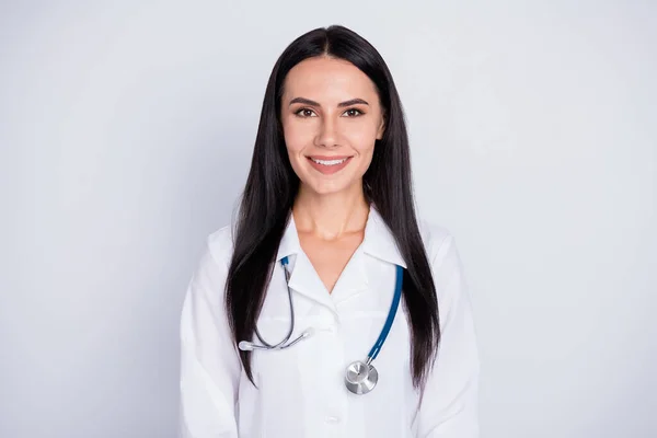 Todo está bien. Foto de la atractiva doctora practicante dama de buen humor amable sonriendo a los pacientes usar bata de laboratorio blanca estetoscopio aislado fondo de color gris — Foto de Stock