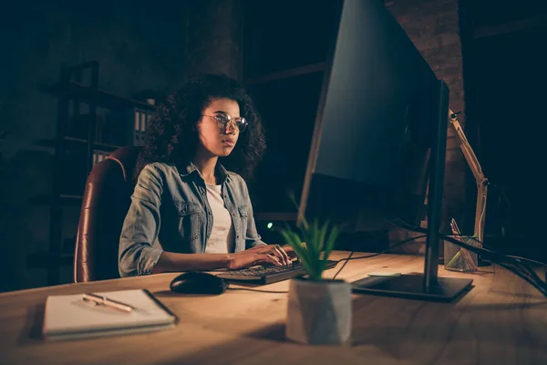Fókuszált képzett start-up szakértő afro amerikai lány cég szabadúszó web rendszergazda ül esti asztali munka számítógép tesztelés új honlap böngésző karbantartás hiba a munkahelyen — Stock Fotó