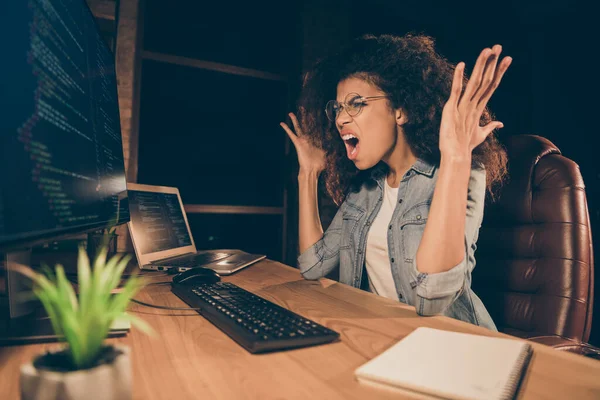 フラストレーションを感じるストレスを受けたアフリカ系アメリカ人の女の子のウェブエンジニアは、テーブルの机に座るコンピュータの仕事は、ワークステーションの職場で怒っているJavaScriptのフロントエンドバックエンドテストエラー悲鳴画面を持っている — ストック写真