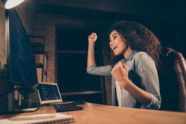 Profiel side photo ecstatic afro american girl it developer sit evening desk work computer hacked artificial intelligence international data raise fists scream yes in workplace workstation — Stockfoto