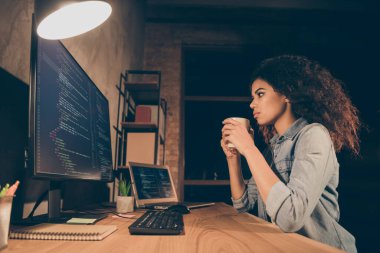 Profile side photo concentrated afro american girl entrepreneur programmer sit table desk use pc work debugging web design need caffeine hold mug beverage in evening workplace workstation clipart
