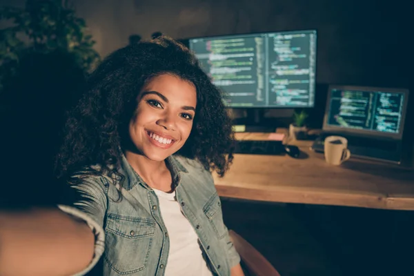 Positieve vrolijke afro-Amerikaanse meisje web designer zitten late avond kantoor maken zelfportret tonen haar java script data beheerder werktafel bureau computer in werkstation werkplek — Stockfoto