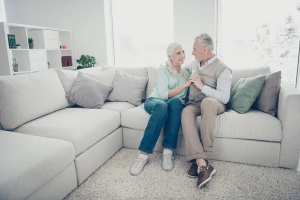 Foto de casal muito velho de mãos dadas comunicando sobre a vida perfeita no amor sentado sofá aconchegante dentro de casa — Fotografia de Stock