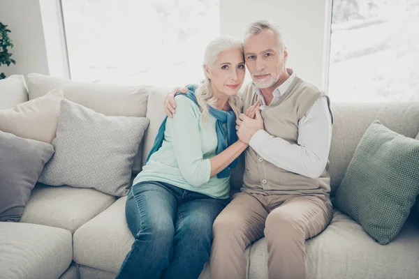 Фото двох красивих літніх людей пара спирається на сімейний портрет, що сидить затишний диван в приміщенні — стокове фото