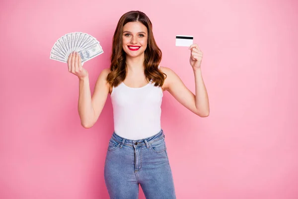 Porträtt av positiva glada flicka hålla pengar fan deposition betalkort rekommenderar att använda bank cashback tjänster lätt betalning bära vit tank-top isolerad över rosa färg bakgrund — Stockfoto