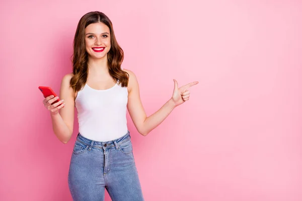 Porträt von positiven fröhlichen Mädchen zeigen Zeigefinger Kopierraum verwenden Handy empfehlen Online-Rabatte tragen weiße Singlet isoliert über rosa Hintergrund — Stockfoto