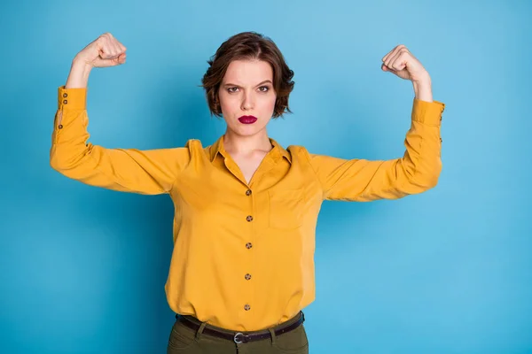 Girls power. Photo of pretty serious lady hold raise biceps two hands showing perfect biceps after gym training wear yellow shirt green pants isolated bright blue color background — Stock Photo, Image
