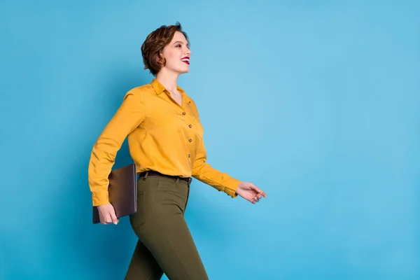 Profil fotó szép üzlet hölgy hold notebook kezek magabiztos munkavállaló séta vállalati konferencia lásd kollégák viselni sárga ing zöld nadrág elszigetelt fényes kék szín háttér — Stock Fotó