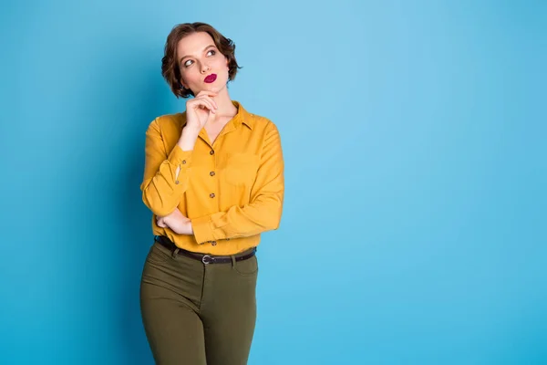 Foto di abbastanza divertente affascinante signora braccio dito sul mento sguardo vuoto spazio candido persona creativa indossare camicia gialla pantaloni verdi isolato luminoso blu colore sfondo — Foto Stock