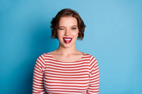 Photo of beautiful pretty cheerful lady playful coquettish person sticking tongue out mouth blinking eye wear casual red white shirt isolated bright blue color background — Stock Photo, Image