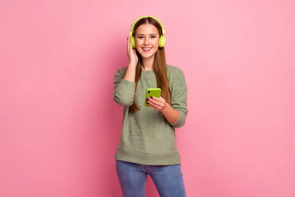 Portret van positieve vrolijke meisje gebruik smartphone luisteren stereo geluid muziek uit haar afspeellijst hebben heldere glans headset wear trui trui geïsoleerd over pastel kleur achtergrond — Stockfoto