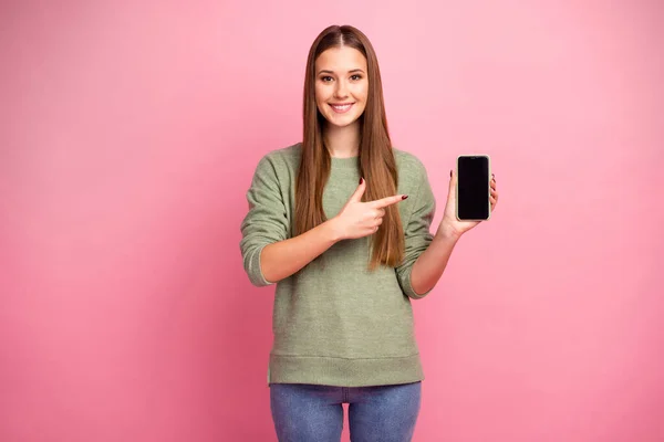 Retrato de positivo alegre menina segurar smartphone indicador de ponto dedo demonstrar novo dispositivo aconselhar escolher desgaste bom look suéter isolado sobre fundo cor pastel — Fotografia de Stock