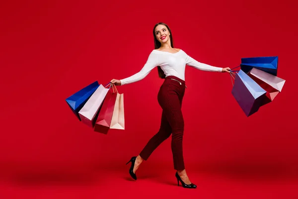 Full size foto van elegante trend dame klant gaan lopen stap genieten winkelen wandeling gaan stap houden veel tassen dragen witte trui geruite broek schoenen geïsoleerd over heldere glans kleur achtergrond — Stockfoto