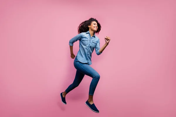 Foto lateral de perfil de cuerpo completo de la joven afroamericana activa salto rápido después de la primavera descuentos viernes negro desgaste traje de estilo casual aislado sobre fondo de color rosa —  Fotos de Stock