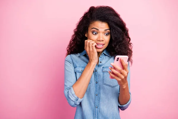 Retrato de menina frustrada usar smartphone ler informações de mídia social obter desgosto notificação mordida unhas desgaste jeans camisa isolada sobre cor rosa fundo — Fotografia de Stock