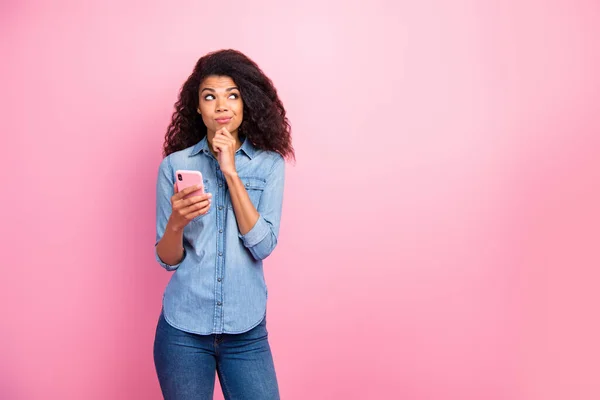 Retrato de una bloguera afro-americana con mentalidad que piensa que los pensamientos tienen dilema qué tipo de dedos de la barbilla de sms touch usan jeans aislados sobre fondo de color rosa — Foto de Stock