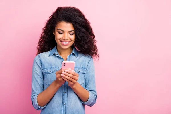 Portrait von positiven fröhlichen afroamerikanischen Mädchen mit ihrem Smartphone lesen Social Network News genießen Spaß tragen trendiges Outfit isoliert über rosa Hintergrund — Stockfoto