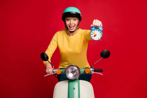 Portret podekscytowany energiczny dziewczyna jeździć jej szybki motocykl trzymać show zegarek cieszyć się jej sportowe wyniki wyścigowe nosić żółty pullover izolowane na jasny połysk kolor tła — Zdjęcie stockowe