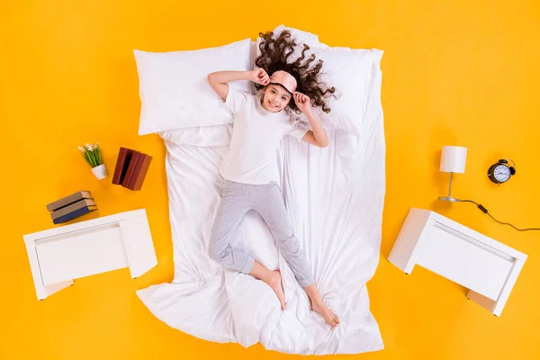 Full length high angle above flat lay view photo of pretty little lady lying comfy morning bedroom sheets wear pajama sleeping mask isolated yellow color background