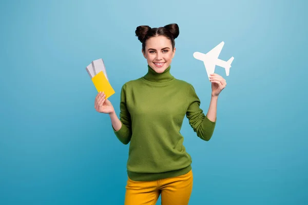 Fénykép a vonzó hölgy tartsa papír repülőgép útlevél jegyek tanácsadás repülő módja utazó függő utas viselni zöld garbó sárga nadrág elszigetelt kék háttér — Stock Fotó