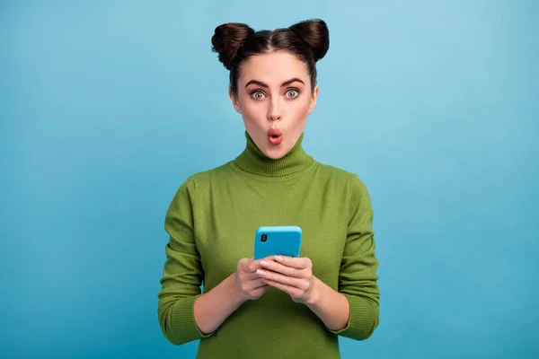 Foto van aantrekkelijke geschokte tiener dame open mond browsen telefoon lees blog post opmerkingen verslaafde smart phone gebruiker dragen groene coltrui geïsoleerde blauwe kleur achtergrond — Stockfoto