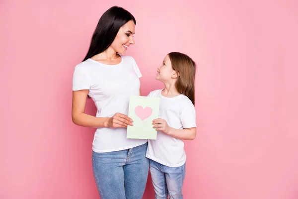 Foto av charmiga söta mamma lilla dotter damer hålla 8 mars vykort känslor kramar ser ögon bära casual t-shirts jeans isolerad pastell rosa färg bakgrund — Stockfoto
