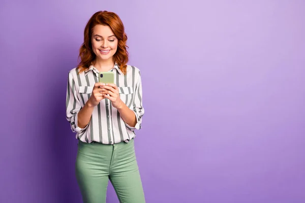 Portret van positieve vrolijke vrouw gebruik smart phone lees sociale netwerk informatie dragen goed kijken kleding geïsoleerd over violet kleur achtergrond — Stockfoto