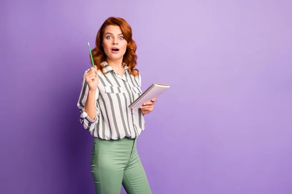 Retrato de mujer sorprendido escribir historia hacer informe pensar pensamientos conseguir idea impresionado gritar wow omg levantar lápiz hasta usar ropa verde con estilo aislado sobre fondo de color violeta —  Fotos de Stock