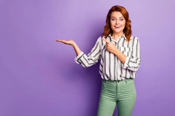 Retrato de mujer sorprendido promotor celebrar la mano presente promoción anuncios dedo índice indican gritar impresionado wow omg desgaste ropa elegante aislado sobre fondo de color púrpura —  Fotos de Stock