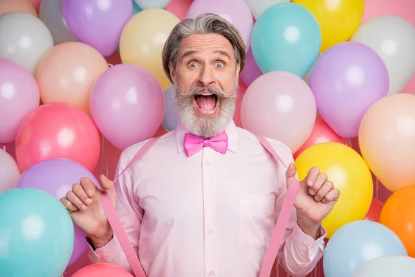 Close-up portrait of his he nice attractive overjoyed funny cheerful cheery grey-haired mature man having fun pulling suspenders isolated over pink pastel color background