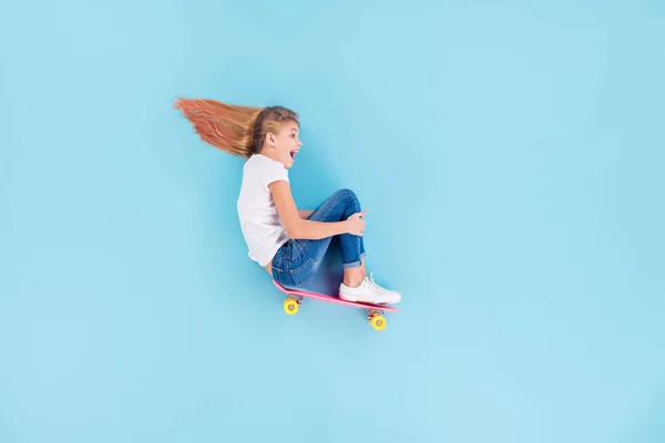 上上高い角度ビュープロフィール側フル長いです写真の興奮した精力的な子供の女の子乗りスケートボードから高い斜面感じ喜び悲鳴レイ上に隔離された青の色の背景 — ストック写真