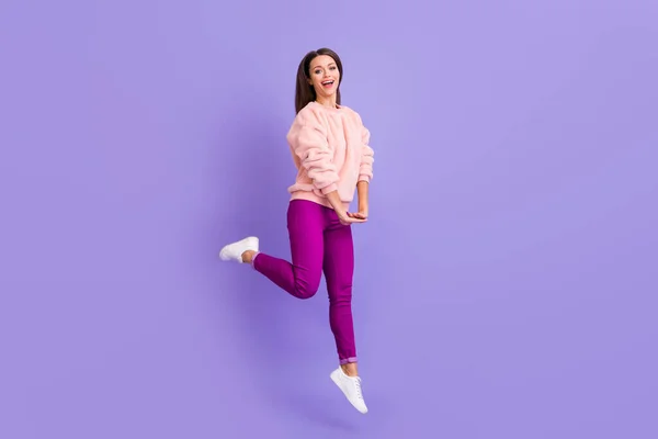 Foto de perfil de cuerpo completo de la señora extática divertida saltando alto regocijo pasar precioso tiempo libre desgaste casual piel suave suéter pantalones zapatillas aisladas color púrpura fondo —  Fotos de Stock