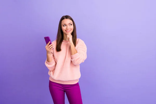 Photo of pretty addicted blogger lady hold telephone thinking over creative new post text idea minded wear casual fur fluffy pullover pants isolated purple color background — Stock Photo, Image
