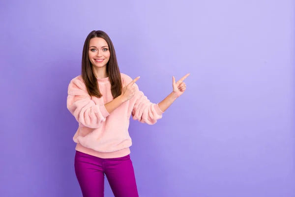 Gorąca sprzedaż. Zdjęcie niesamowite pani wskazując palec pusty przestrzeń oferta nowe ubrania sklep nosić casual ciepłe puszyste pulowery spodnie odizolowane fioletowy kolor tła — Zdjęcie stockowe