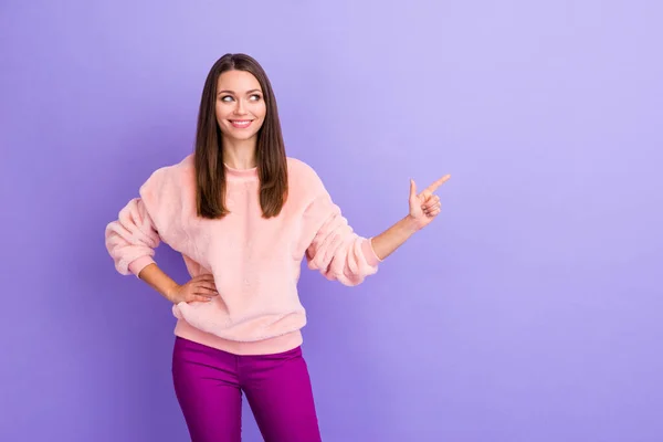 Foto de senhora bonita indicando espaço vazio dedo apresentando nova lista de preços loja shopping loja de roupas desgaste casual quente pulôver macio calças isoladas cor roxa fundo — Fotografia de Stock