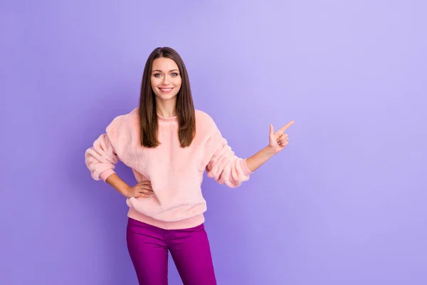 Bild av fantastisk dam indikerar finger tomt utrymme presenterar nya prislista butik köpcentrum kläder butik bära casual varm luddig pullover byxor isolerad lila färg bakgrund — Stockfoto